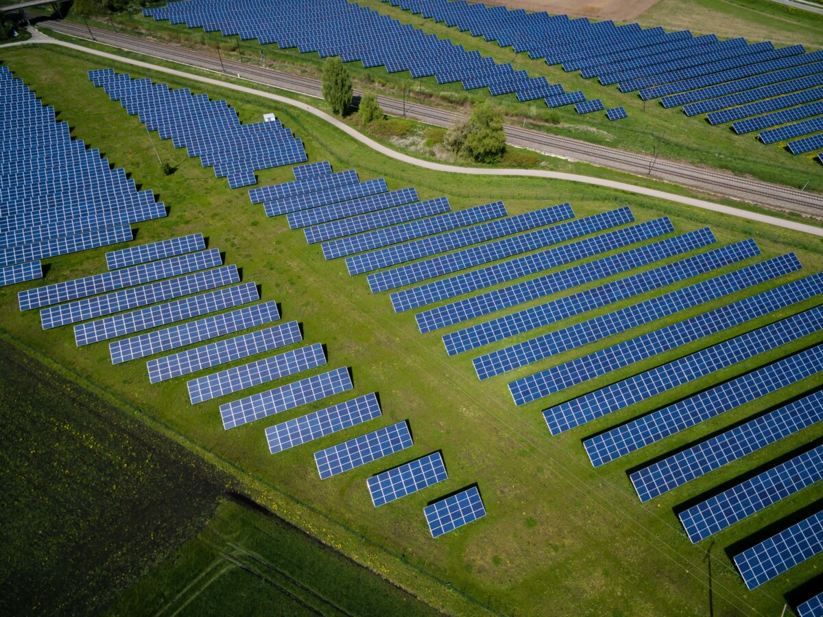 Feld mit Photovoltaik-Anlagen auf grüner Wiese.